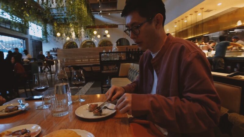 A Man Wearing Glasses and A Maroon Jacket Is Dining at Bavel Restaurant in Los Angeles