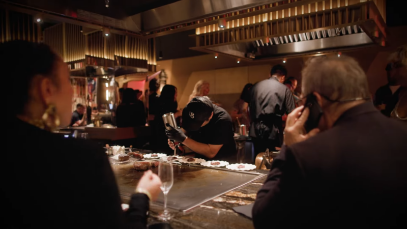 A Chef at Maison Kasai in Downtown LA Prepares Gourmet Dishes on A Grill While Diners Enjoy the Lively Atmosphere of The Restaurant