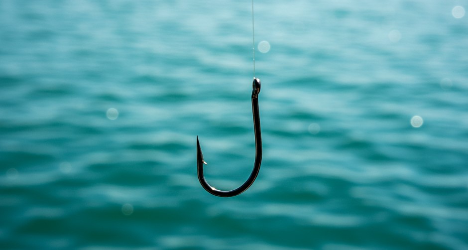 A single fishing hook hangs suspended above the rippling turquoise water